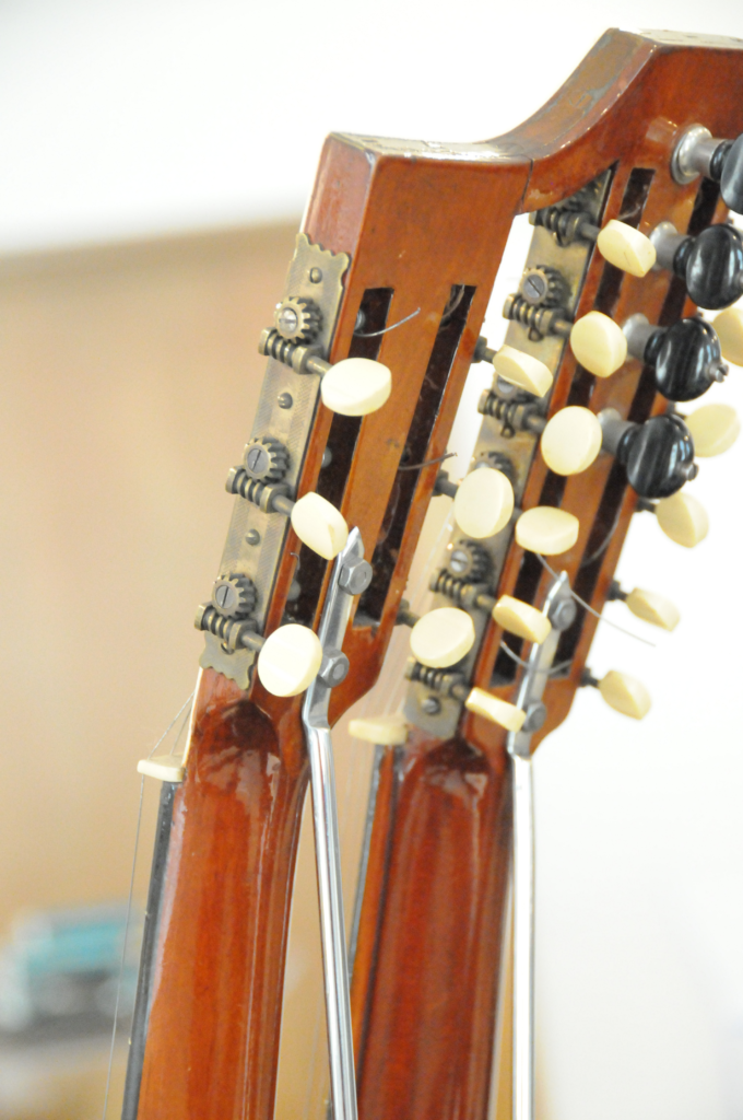 A close-up of the guitar's two necks and tuning pegs.